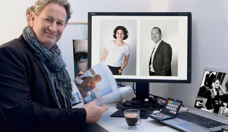 Portrait de Franck Jonville photographe corporate marseille aix en provence région sud homme photographe en veste assis devant ordinateur de bureau affichant des portraits professionnels